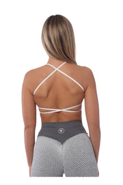 A woman in a sports bra with cross back and open back design, part of the Nakd Collection.