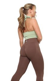 A woman in chocolate brown scrunch bum gym leggings, showcasing a close-up of her back and legs. Empower your workouts with curve-defining, high-waisted leggings for ultimate support and style.