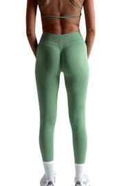 Woman wearing green V Back scrunch bum leggings, close-up of clothing details.
