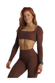 A woman in a long-sleeved chocolate top with a cross-front design, showcasing support and style. Size guide: S, M, L. Model wears size small (UK 8).