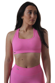 Woman in pink sports bra with cross back design, close-ups of chest, belly, lips, neck, and nose.