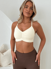 Woman wearing The Aura Collection - Scrunch Longer Line Soft Bra in Cream, posing with hands on hips, showcasing the bra's soft fabric and flattering fit.