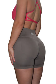 Woman in pink shirt and grey tights, showcasing Ultimate Contour Collection - Non Scrunch Butt Lifting Gym Shorts for enhanced curves and support during workouts.