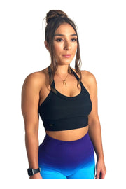 Side angle of a woman wearing the Signature Collection Black Halter Neck Sports Bra with purple leggings